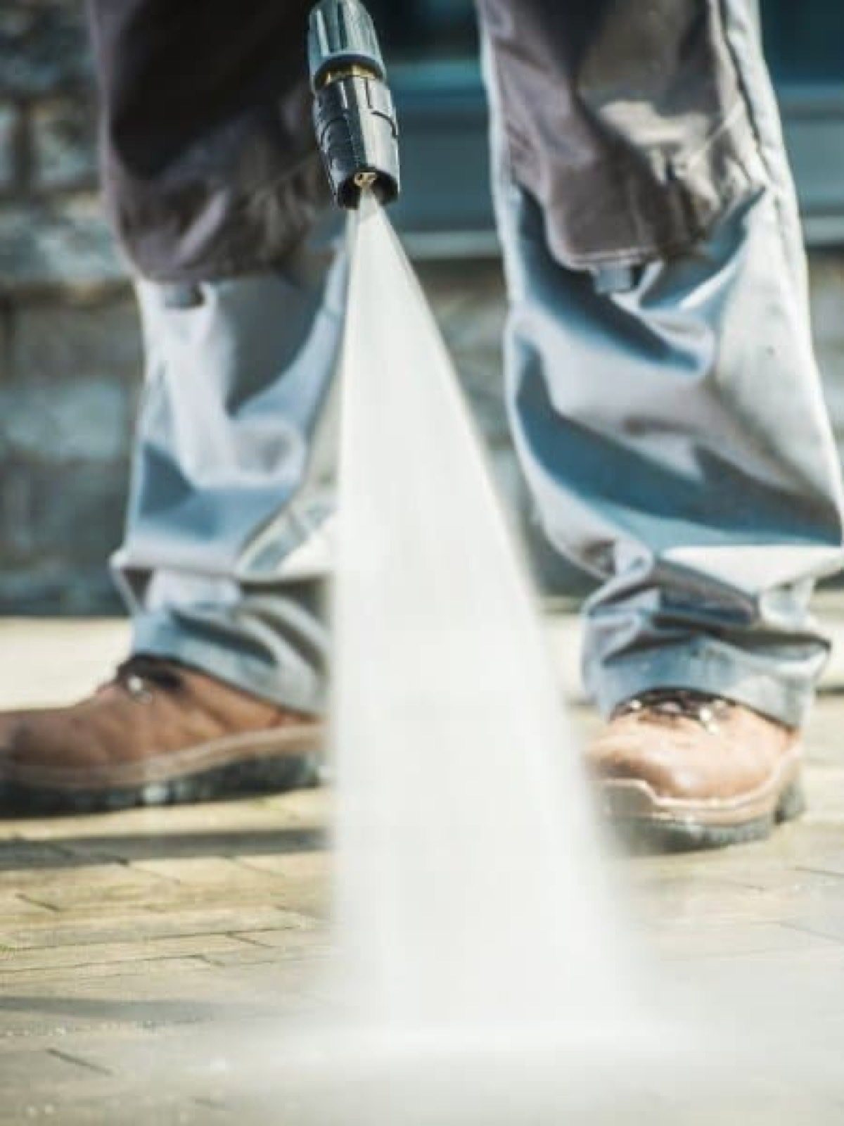 Close-up of a pressure washer wand cleaning concrete