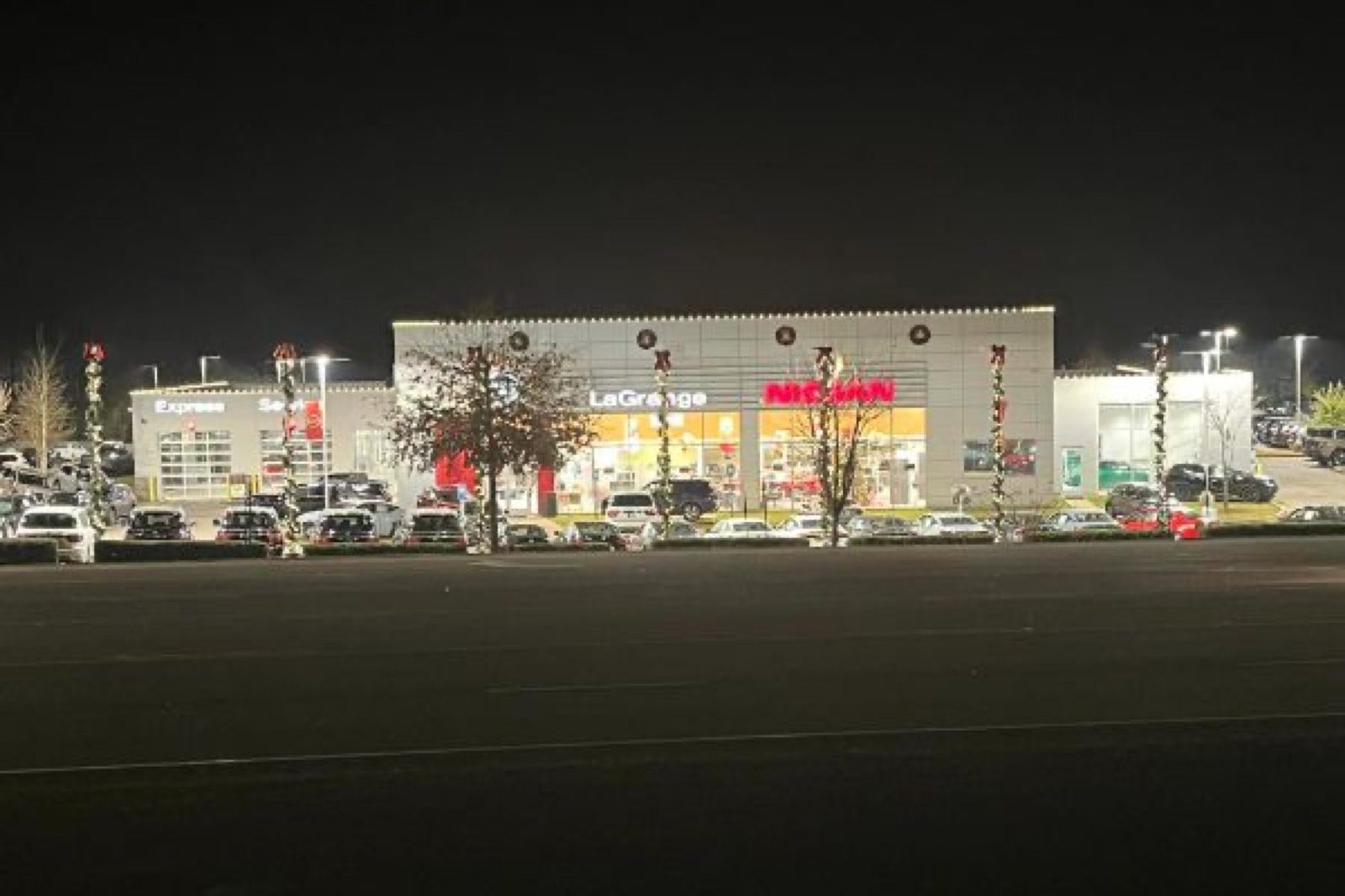 Car dealership storefront decorated with lights and wreaths